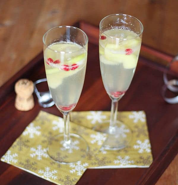 Apple, Pear and Pomegranate Sangria in champagne flutes on yellow napkins