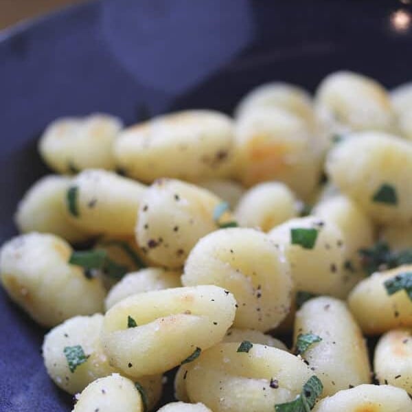 gnocchi with sage and black pepper in a pile on blue plate