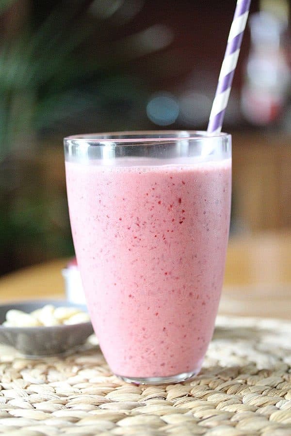 side view of cherry almond smoothie with purple straw