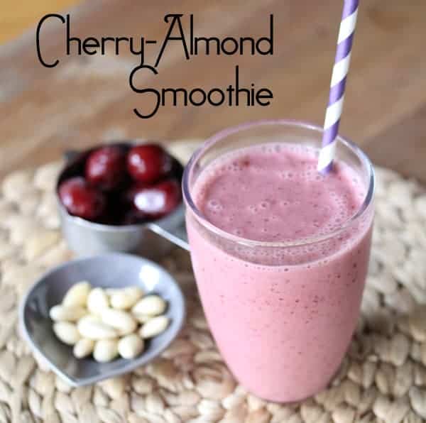 Cherry Almond Smoothie in a glass with fresh cherries and almonds next to it