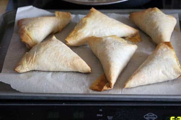 Six Kale Spanakopitas on parchment lined baking pan after baking