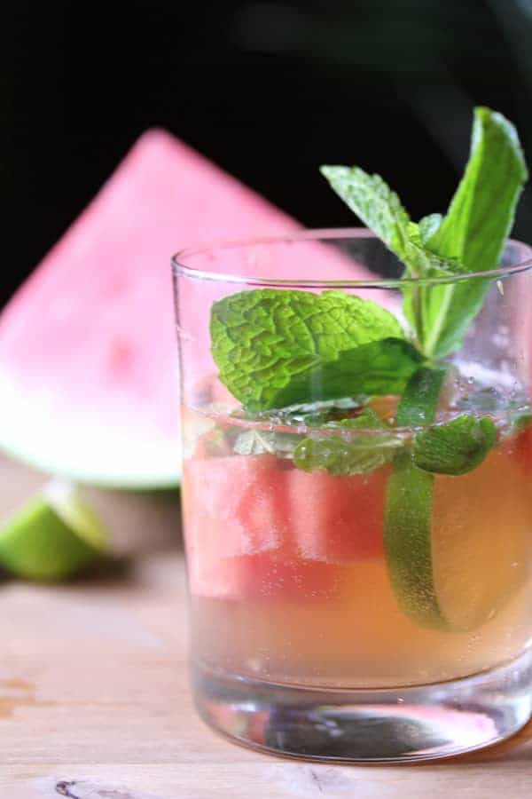 Side view of Watermelon Sangria in a glass with fresh mint sprig and watermelon chunks