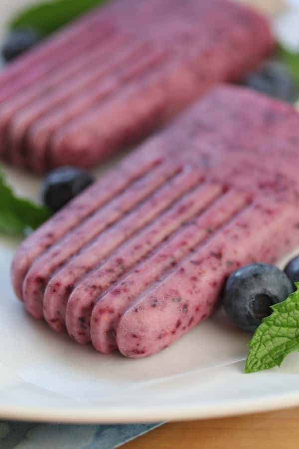 Close up shot of Blueberry Mint Yogurt Popsicleson a white plate