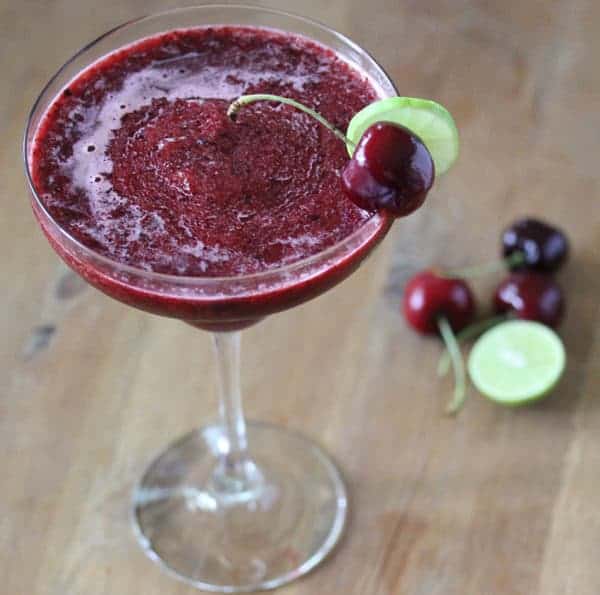 Frozen Cherry Limeade in a margarita glass with fresh cherry and lime garnish