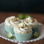 three key lime cupcakes with white chocolate frosting and salted pistachios on white plate