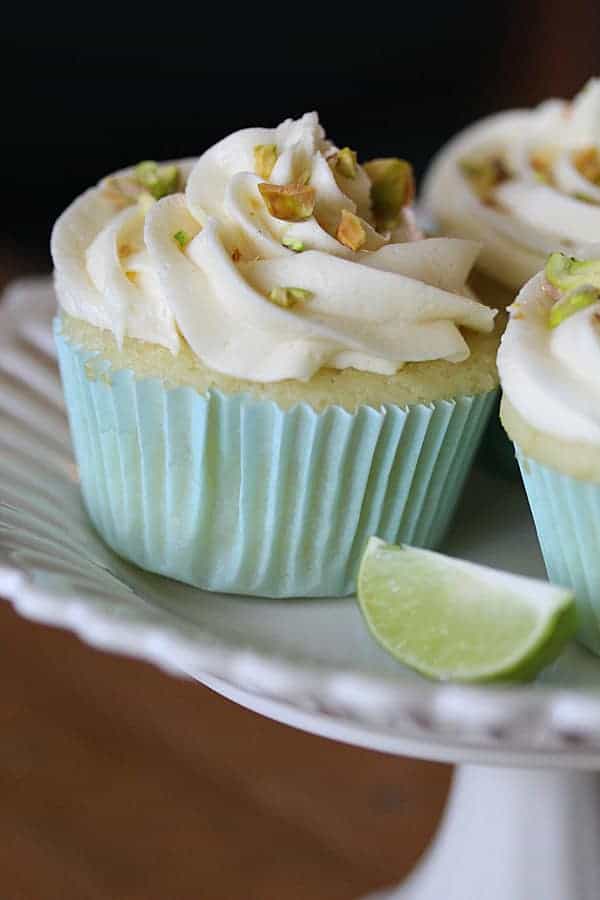 Side view of Key Lime Cupcakes with White Chocolate Frosting and lime wedge