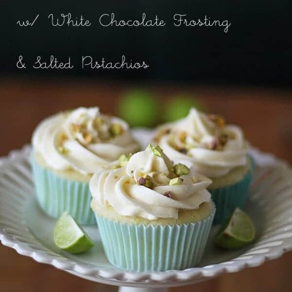 three key lime cupcakes with white chocolate frosting and salted pistachios on white plate