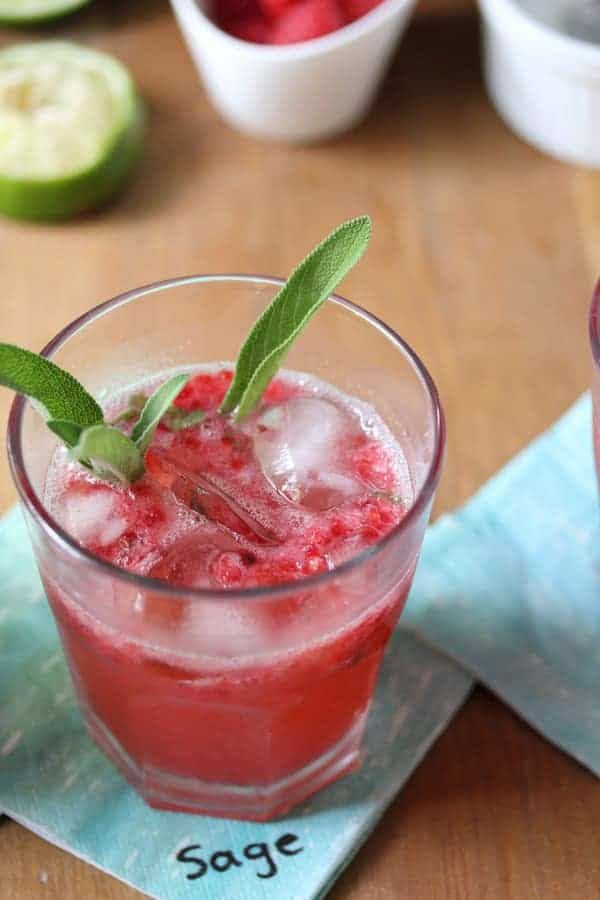 Close up view of Raspberry Herb Smash Cocktail with fresh sage leaf