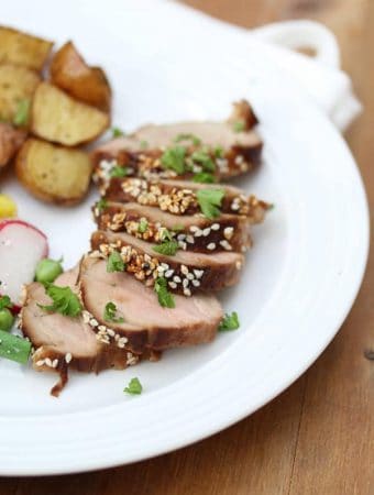 sriracha and sesame glazed pork tenderloin on plate with potatoes and vegetables