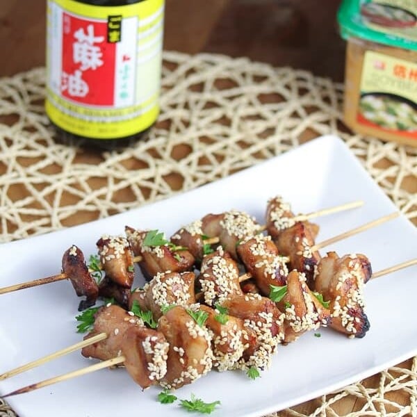 three miso and sesame grilled chicken kebabs on white tray