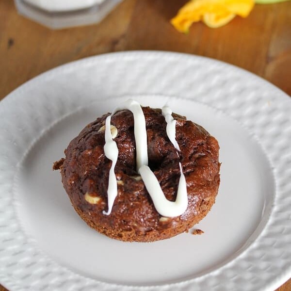 chocolate and zucchini baked donuts with white glaze on white plate