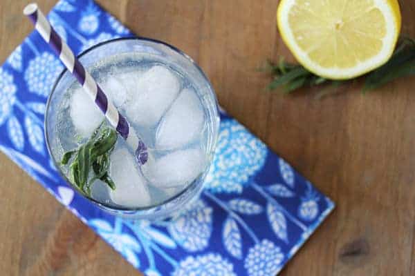 Overhead shot of Lemon Tarragon Spritzer in a glass with a striped straw and half lemon