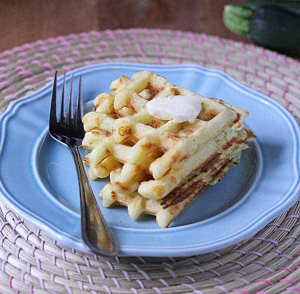 Stack of two Cheddar and Cornmeal Waffles on a blue plate with a fork