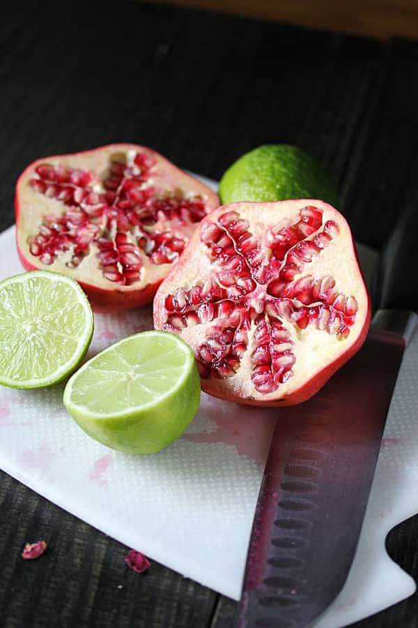 Fresh pomegranate cut in half with a whole lime cut in half next to it