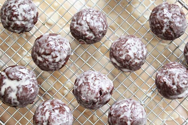 Ten Chocolate Donut Holes with glaze cooling on a wire rack 