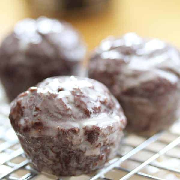 Close up shot of three Chocolate Glazed Donut Holes on a wire rack