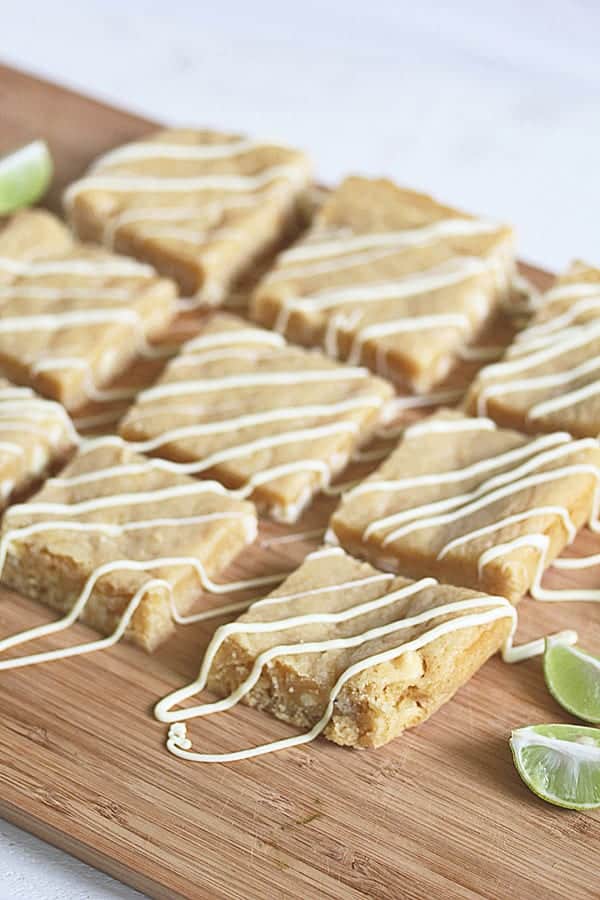 Rows of Key Lime Blondies on wood board with white chocolate drizzled over top