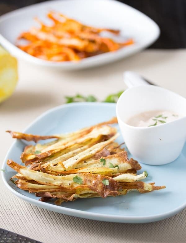 crispy baked carrot hips with spicy harissa yogurt dip in white bowl