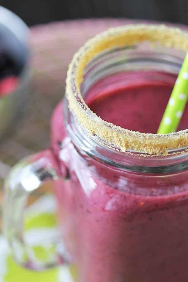 Close up view of Triple Berry Pie Smoothie in a mason jar with green straw