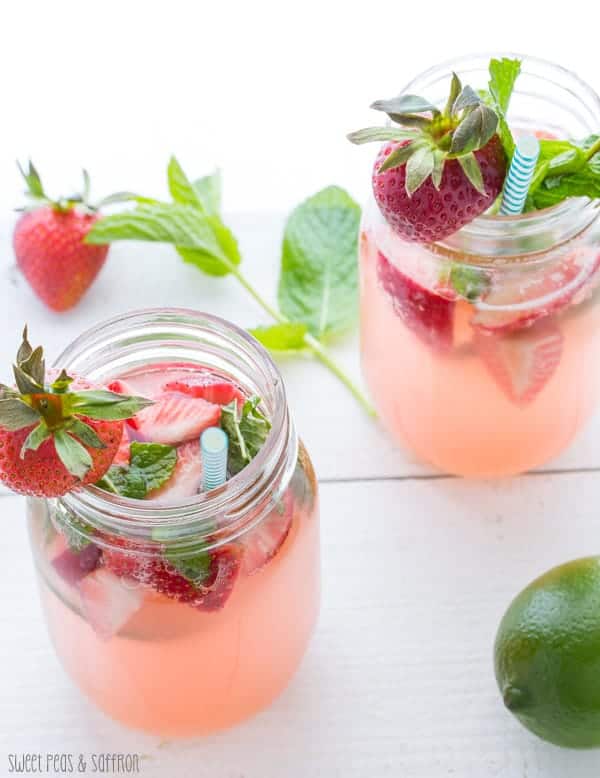Overhead shot of the Rosé Sangria in two mason jars with fresh strawberries, mint, and a lime