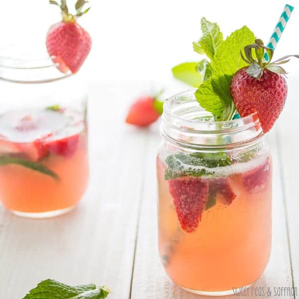 Rosé Sangria in two mason jars with fresh mint, strawberries, and a striped straw