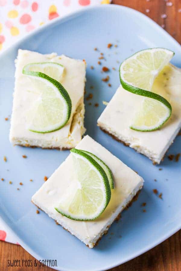 Three Lime Cheesecake Bars on a blue plate with lime garnish