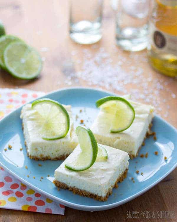 Three Lime Cheesecake Bars on a blue plate with fresh lime garnish