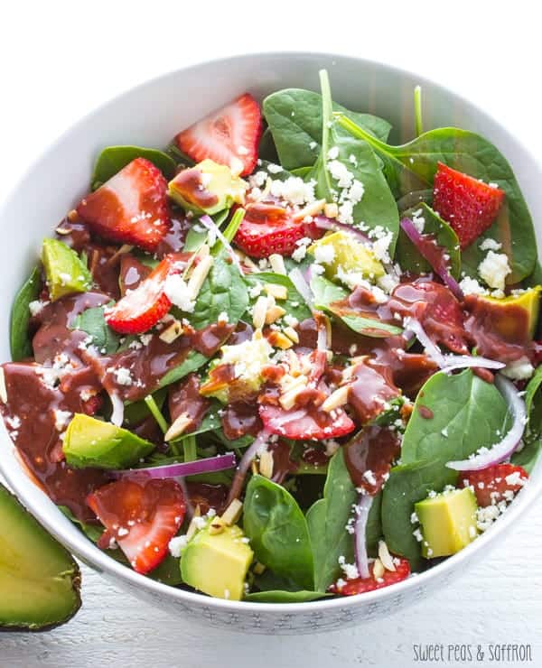 bowl of strawberry spinach salad with vinaigrette poured over it