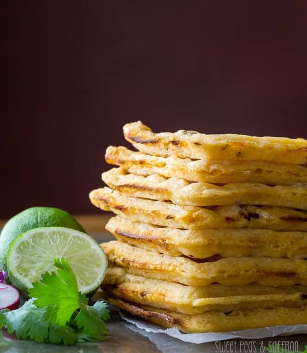 Stack of eight Chipotle-Cornmeal Waffles with fresh lime and cilantro next to it