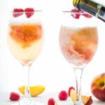 two peach reaspberry bellinis in wine glasses
