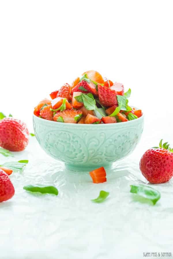 Strawberry Bruschetta in a blue bowl with fresh whole strawberries around it