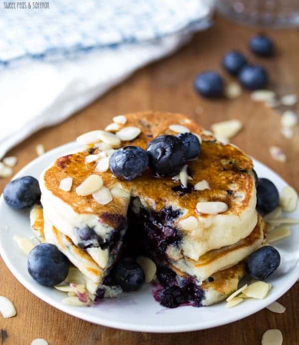 Stack of three Almond Blueberry Pancakes with a slice taken out of them