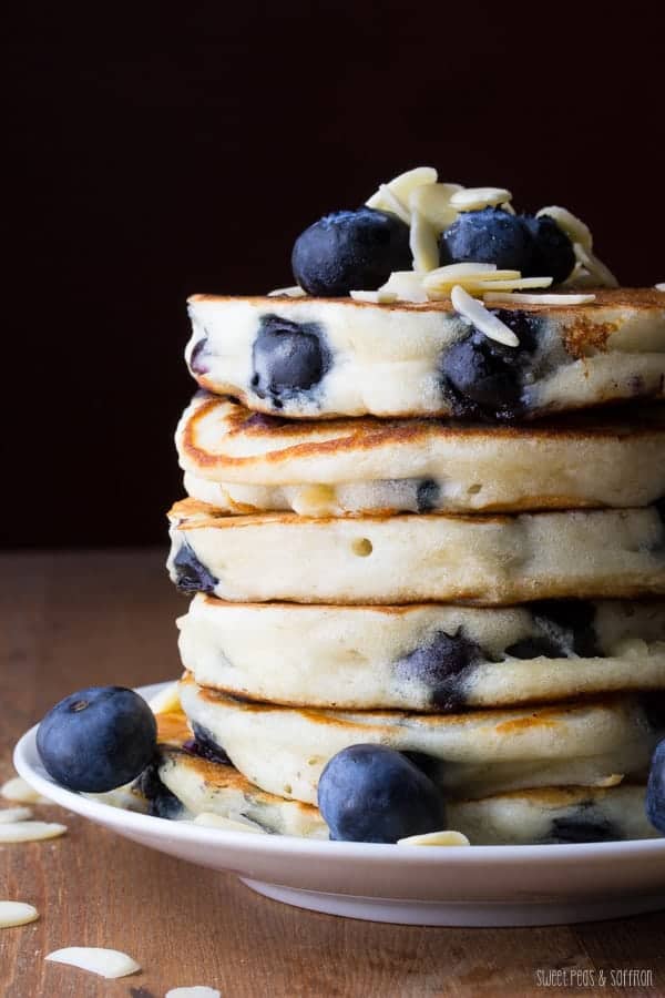 Stack of six Almond Blueberry Pancakes on plate with fresh blueberries on top