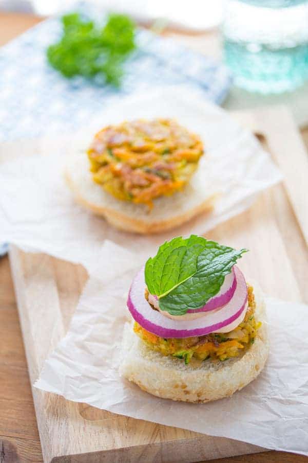 Mini Moroccan Chickpea Burgers on an open bun with sliced red onion and a mint leaf