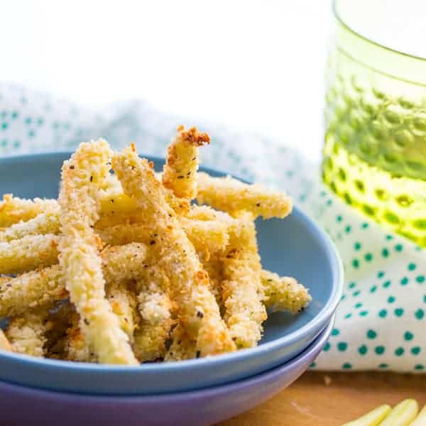 Close up view of Crispy Parmesan Baked Green Bean Fries in stacked blue bowls