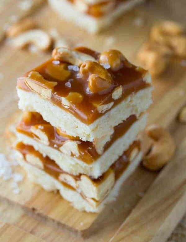stack of three salted caramel bars with cashews on wood board