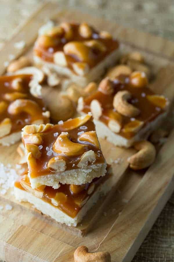 Stack of Cashew Salted Caramel Bars arranged on a wood cutting board