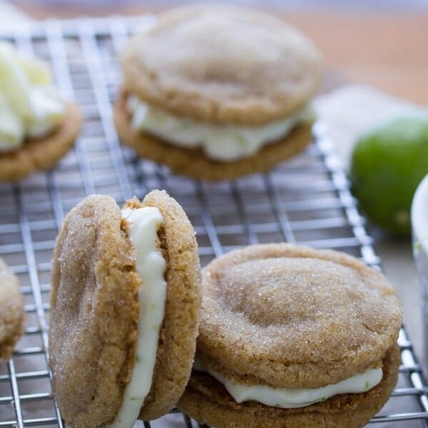 five key lime pie sandwich cookies on wire rack with lime in background