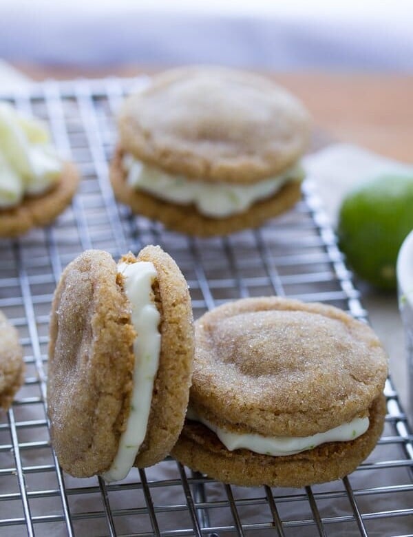 five key lime pie sandwich cookies on wire rack with lime in background