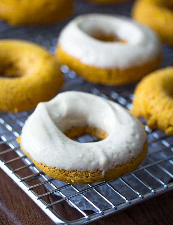 four baked pumpkin donuts with cream cheese on wire rack