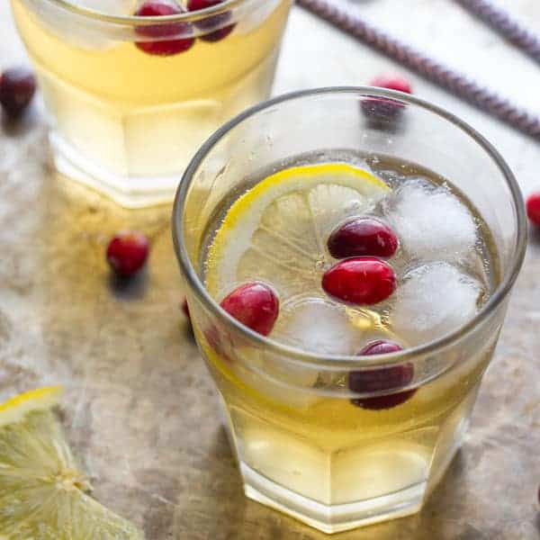 Two glasses of Cranberry Ginger Cider Cocktail with whole cranberries and lemon slice