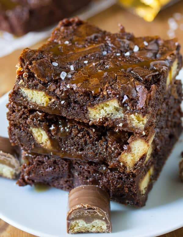 Stack of three brownies on a plate with twix bar on the side