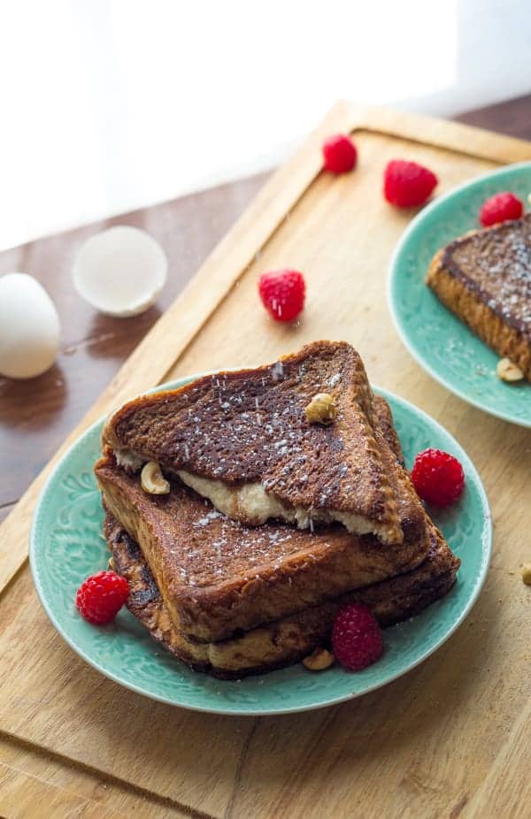 Mascarpone Stuffed French Toast stacked on plate with icing sugar falling over it