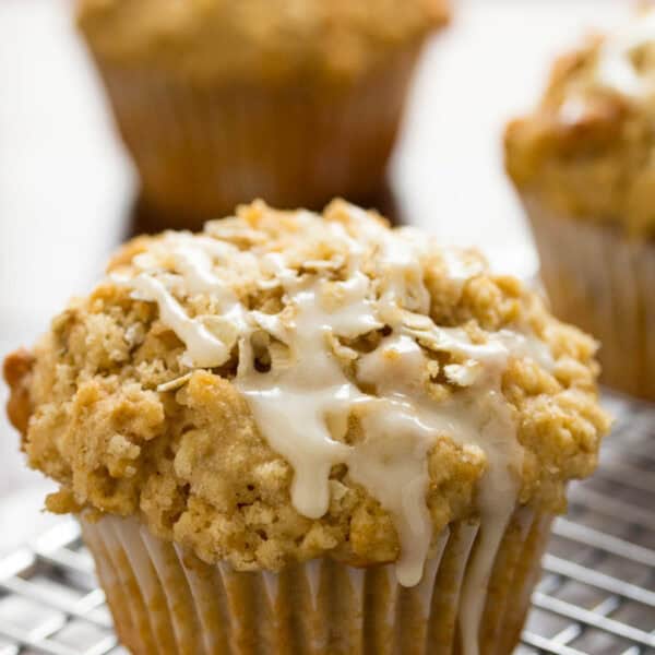 a close up shot of oatmeal muffins with a glaze dripping off the top