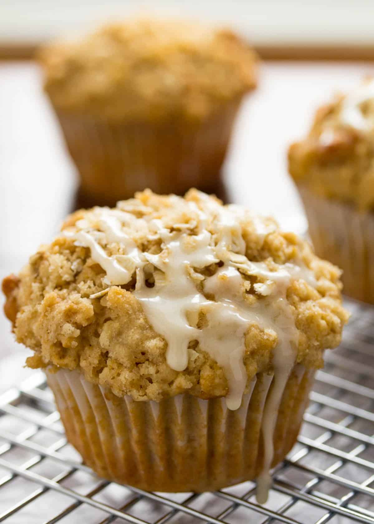 a close up shot of oatmeal muffins with a glaze dripping off the top