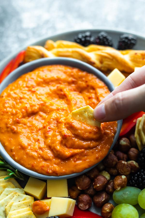 cracker scooping up roasted red pepper dip