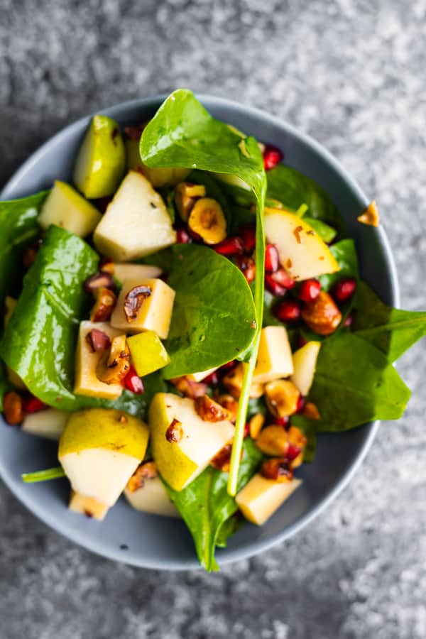 overhead view of spinach pear salad, with ingredients tossed together