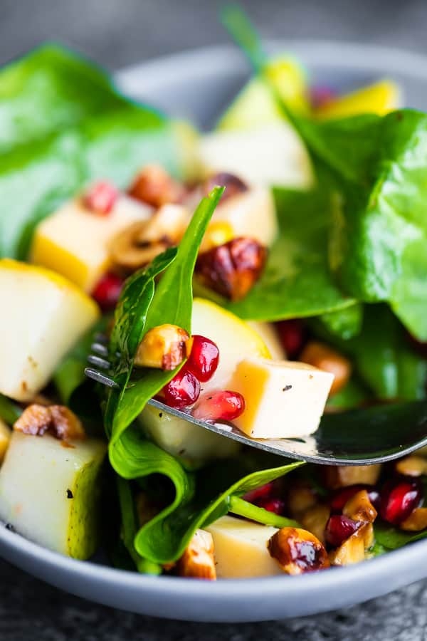 close up view of pear salad with pomegranates on fork