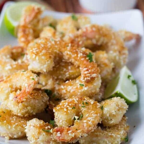 pile of crispy sesame shrimp with lime wedges