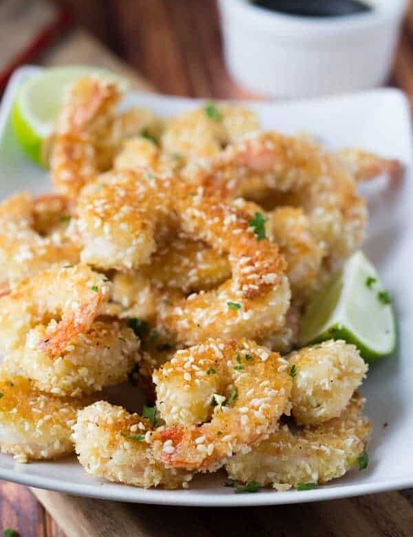 pile of crispy sesame shrimp with lime wedges